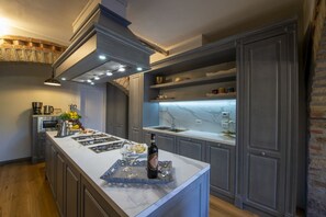 A modern kitchen with a marble countertop, stainless steel appliances, and a built-in oven. - MyExclusiveItaly - Villa Chianti with infinity pool and vineyard view (Greve in Chianti)