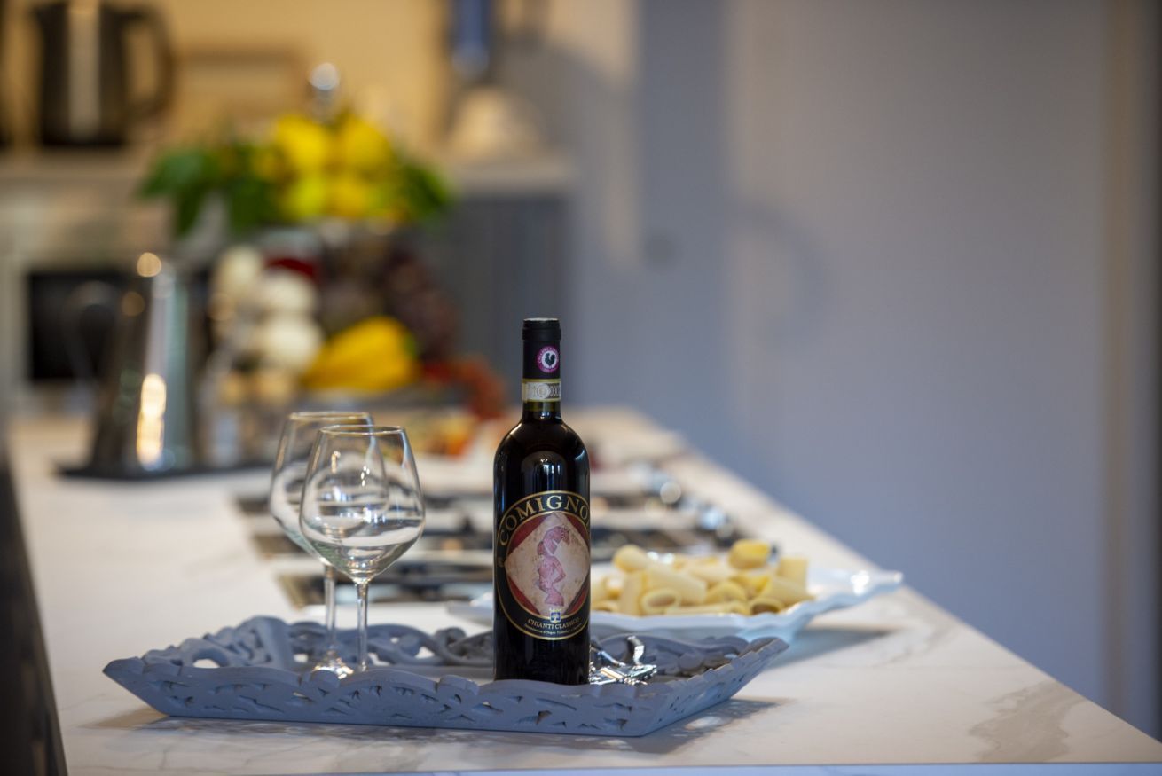 A table with a bottle of Comingo Brut Cuvée, a glass of water, and a plate of pasta.