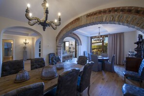 A dining area with a wooden table, upholstered chairs, and a chandelier.