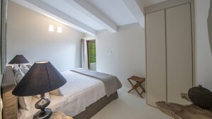 Ein Schlafzimmer mit Bett, Nachttisch, Lampe und Blick ins Freie.
