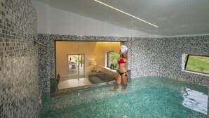 Ein Innenpool mit Mosaikfliesen und Blick ins Freie.