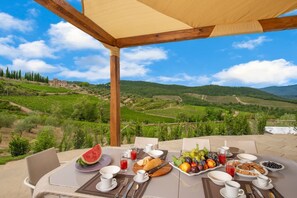 Une table dressée pour le petit-déjeuner, avec une vue imprenable sur un vignoble.