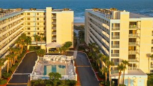 A multi-story hotel with a pool and a view of the ocean. - Seashore Splendor with Ocean views, Heated Pool & Tennis Court (Cocoa Beach)