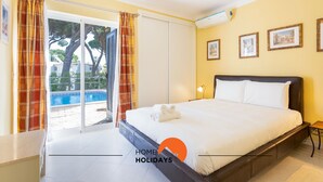 Ein Hotelzimmer mit Bett, einer Schiebetür zum Pool und einer Wand mit gerahmten Bildern.
