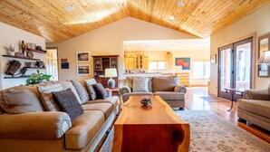 A spacious living room with a wooden ceiling, a large wooden coffee table, and a sofa set.