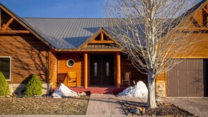 A log cabin with a metal roof, a front porch, and a garage.