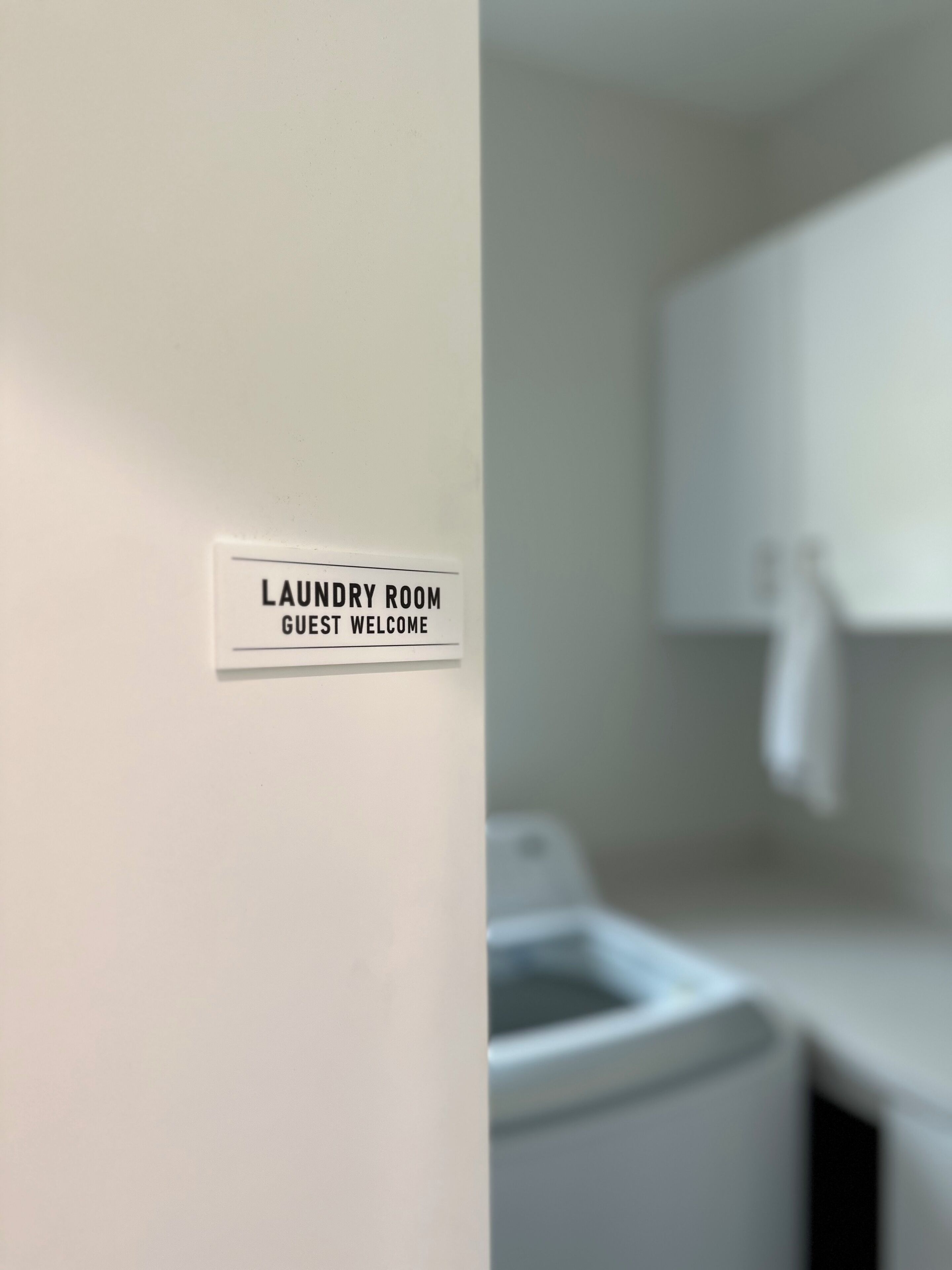 Señal que indica la sala de lavandería con un mensaje de bienvenida para huéspedes.