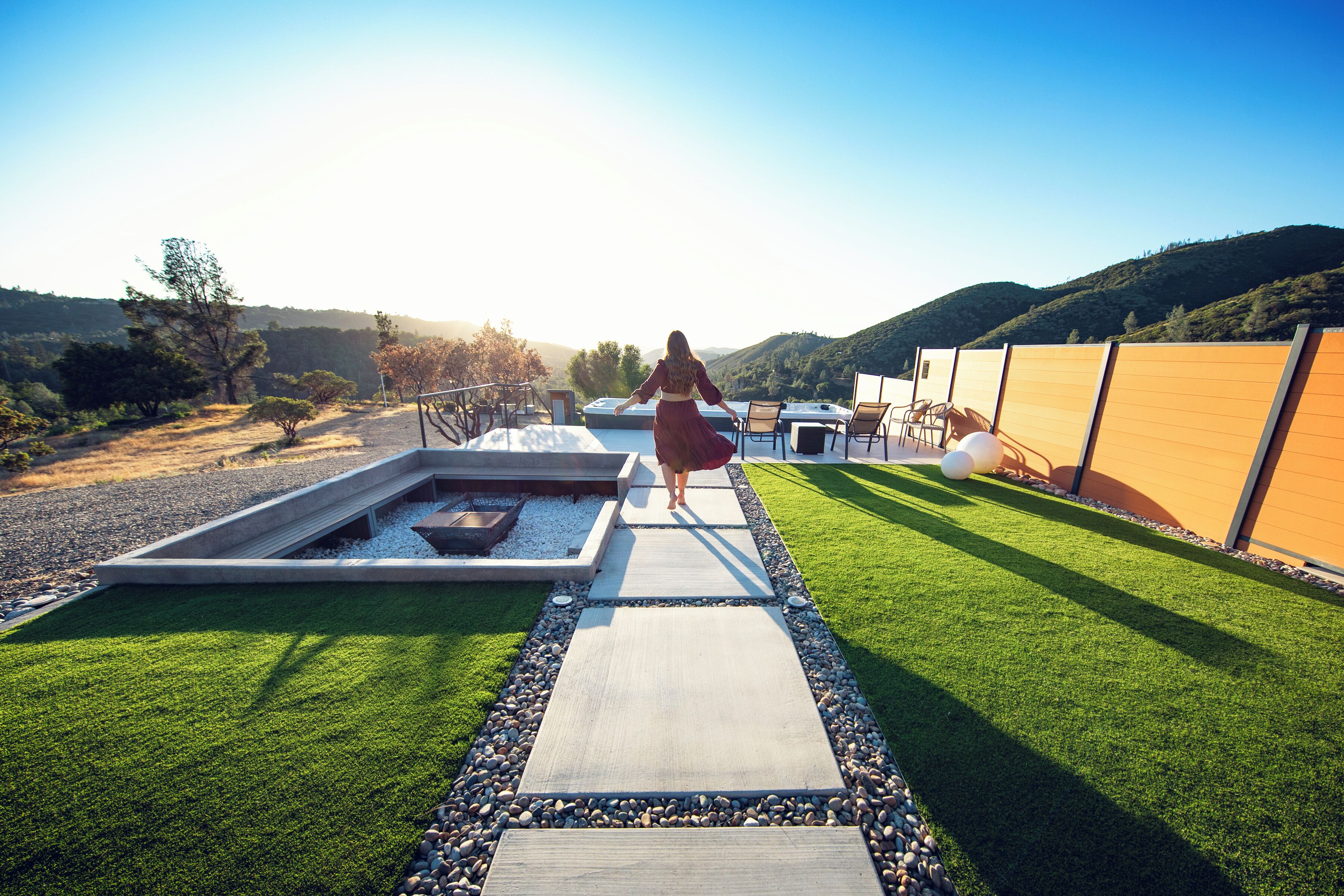 A pathway leading to a pool area with a view of hills in the background.