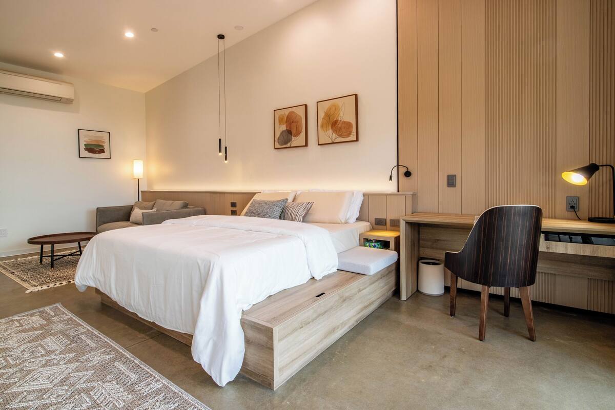 A modern bedroom with a bed, bedside tables, a desk, and a chair.