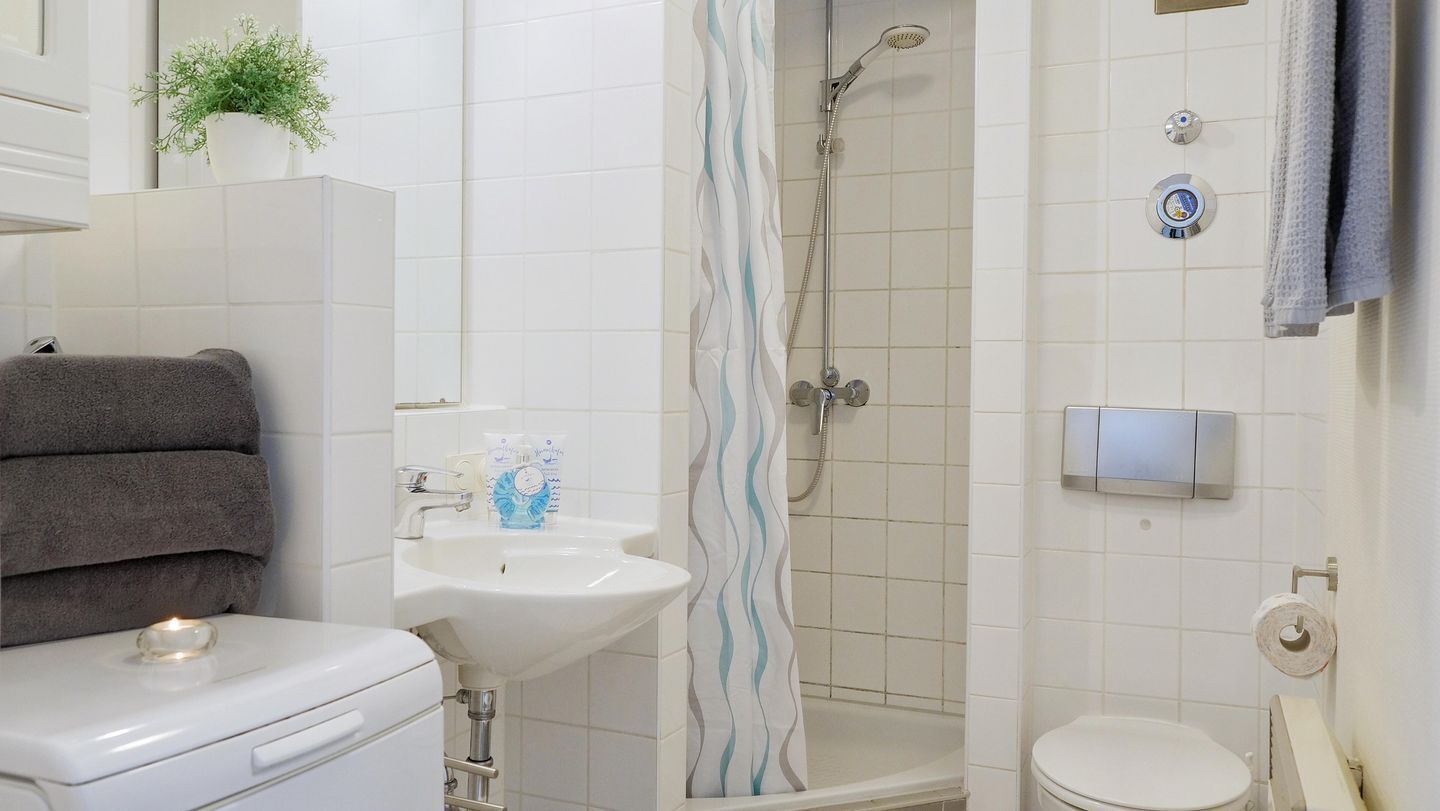 A bathroom with a sink, toilet, shower, and towel rack.