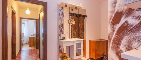 Une salle de bain avec un meuble-lavabo blanc, un miroir et un placard en bois.