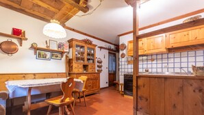 A rustic kitchen with wooden cabinets, a dining table, and a chandelier. - Ski Residence 3B (Falcade)