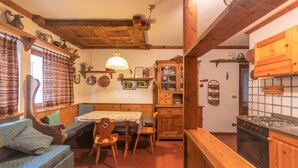 A cozy kitchen with wooden cabinets, a dining table, and a built-in bench. - Ski Residence 3B (Falcade)