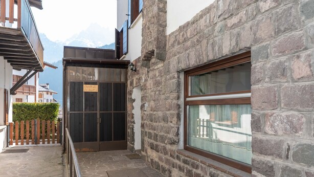 A stone building with a wooden balcony and a window overlooking a mountain. - Villa Simona PT (Falcade)