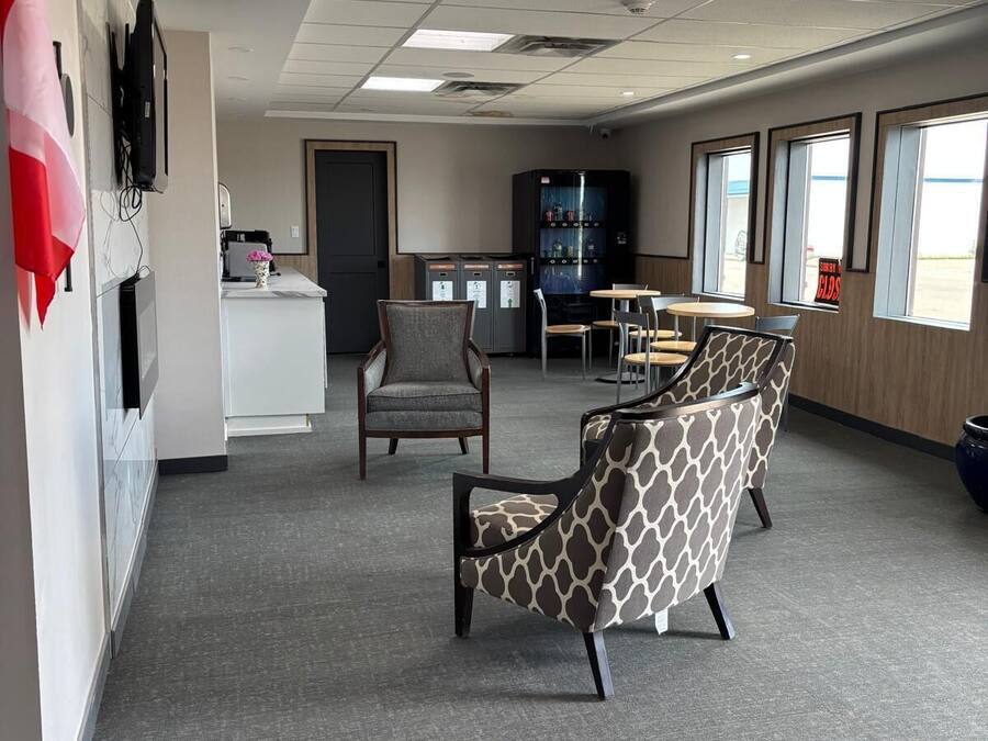 A spacious office with a modern design, featuring a reception area, several seating arrangements, and large windows providing natural light.