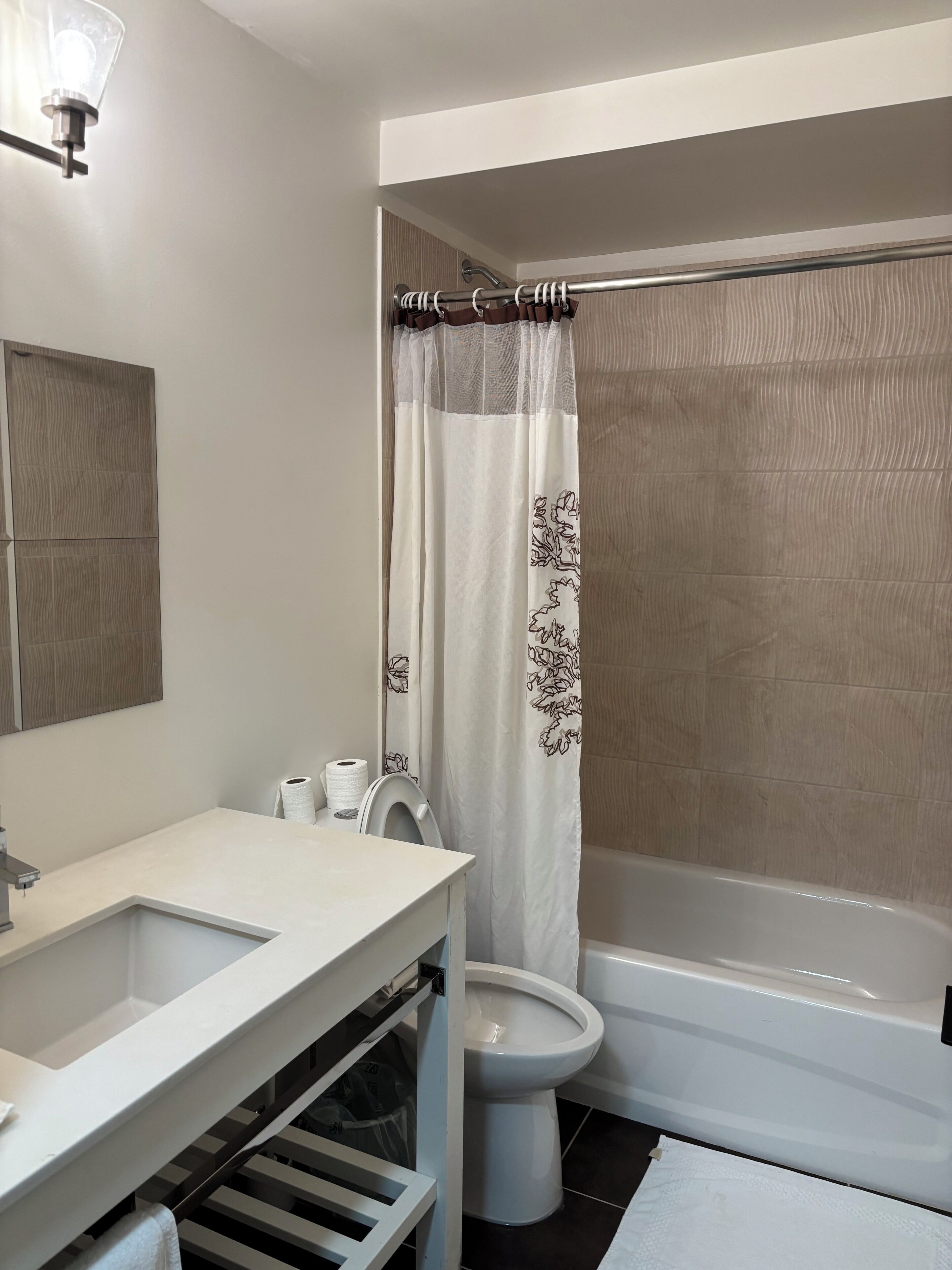 Et badeværelse med toilet, vask og badekar.