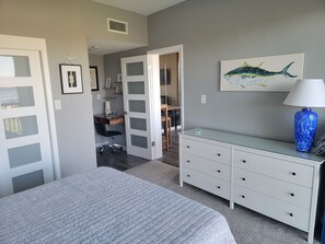 A bedroom with a bed, a desk, and a dresser.