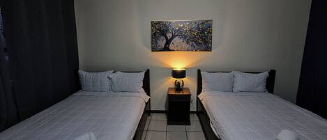 Une chambre d’hôtel avec deux lits, une table de chevet avec une lampe et un tableau au mur.