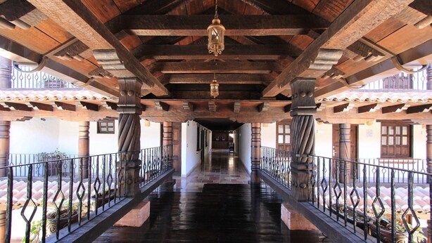 A covered corridor with wooden beams and columns, metal railings, and hanging lanterns. - HOTEL PLAZA SAN CRISTOBAL INN (San Cristóbal de las Casas)