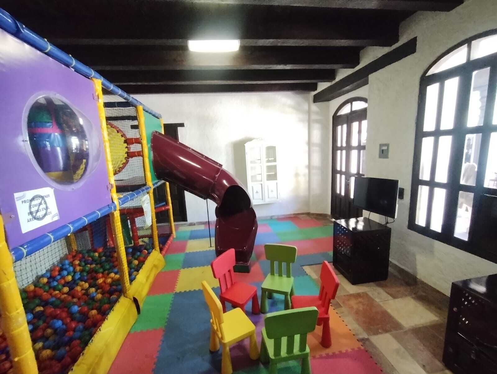 A play area with a slide, colorful mats, and a ball pit.
