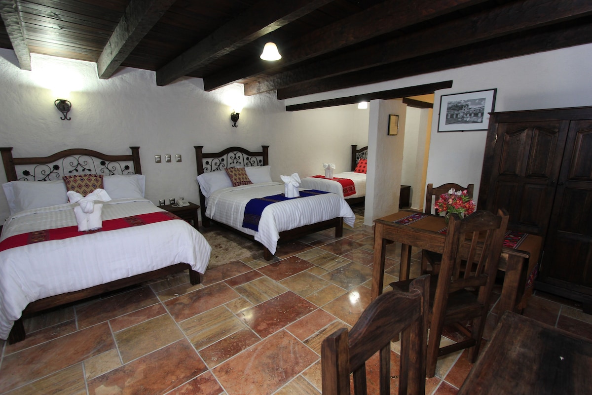 Una habitación de hotel con dos camas, una mesa de madera y una silla.