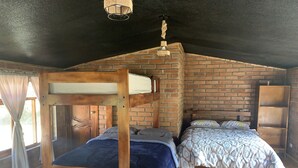 A rustic wooden room with two bunk beds, a brick wall, and a wooden floor. - Quindanna  (Cosanga)