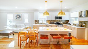 A modern kitchen with a central island, wooden chairs, and pendant lighting. -  Large 3BR Pet-Friendly Apt w/Free Parking Near Red Line-Downtown Boston 82 (Boston)