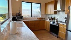 Een moderne keuken met een groot raam, houten kastjes, een roestvrijstalen koelkast en een magnetron.