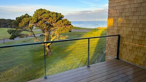 Een balkon met uitzicht op de oceaan en een boom.