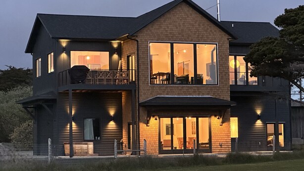 Een huis met twee verdiepingen, een balkon, grote ramen en een helder verlichte entree.
