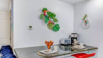 Une cuisine moderne avec un plan de travail en marbre, des tabourets de bar rouges et des œuvres d’art décoratives sur les murs.