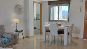 Un espace repas moderne avec une table et des chaises, un canapé, une lampe et une vue sur la cuisine et les montagnes, visible par la fenêtre.