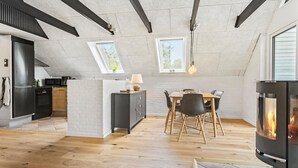 Moderni keittiö, jossa on ruokailutila, takka ja kattovalokuvioita.