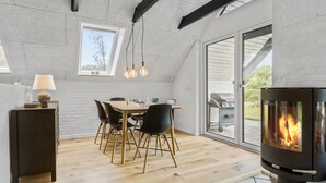 Moderni keittiö, jossa on ruokailutila, sisäänrakennettu puuhella ja suuret ikkunat.