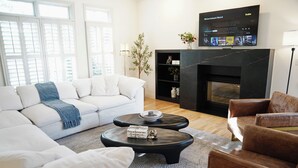 Ein stilvolles Wohnzimmer mit einem weißen Sofa, einem braunen Ledersessel und einem schwarzen Kamin.