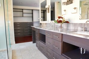 Un bagno moderno con doppio lavabo, mobili scuri e uno specchio grande.