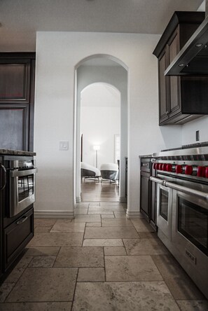 A kitchen with dark cabinets, stainless steel appliances, and a tiled floor.