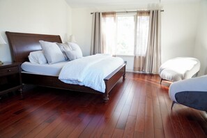 Una camera da letto con un letto di legno, un comodino, una sedia e una finestra con tende.