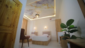 Ein Schlafzimmer mit zwei Betten, einem Holzschrank, einem Schreibtisch und einer Pflanze.