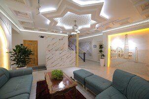 Un lobby espacioso con pared de mármol, una escalera y un gran candelabro.