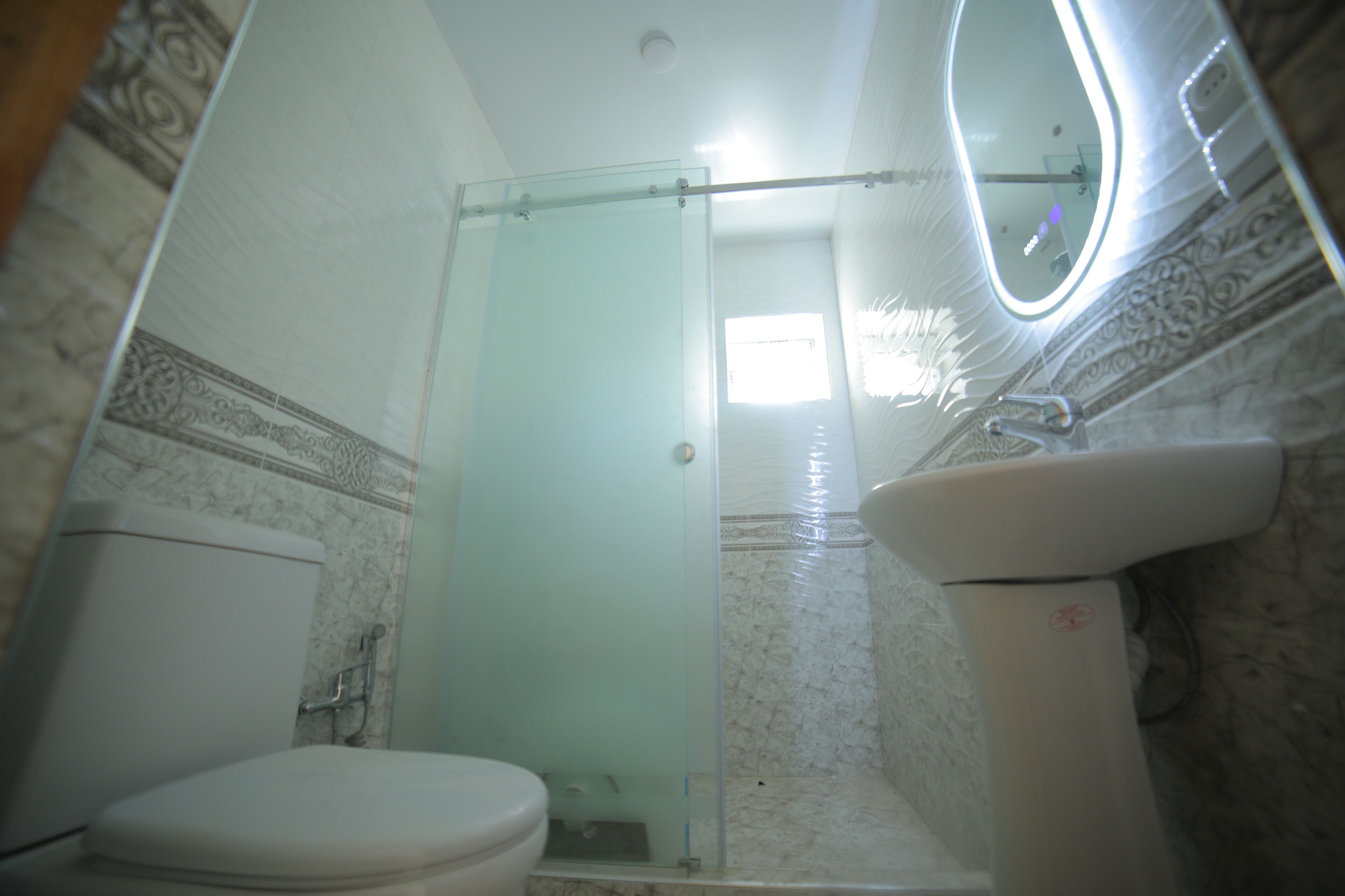 A bathroom with a toilet, a glass shower enclosure, and a sink with a mirror.