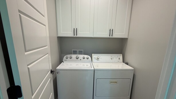 A laundry room with two washing machines and a dryer, white cabinets above, and a wooden floor. - Heritage Cove  Hide Away 
 charming 3 bed
New Albany only 35 min from Oxford. (New Albany)