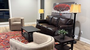 A living room with a leather sofa, a tufted armchair, a small table with a lamp, and a rug. - Heritage Cove  Hide Away 
 charming 3 bed
New Albany only 35 min from Oxford. (New Albany)