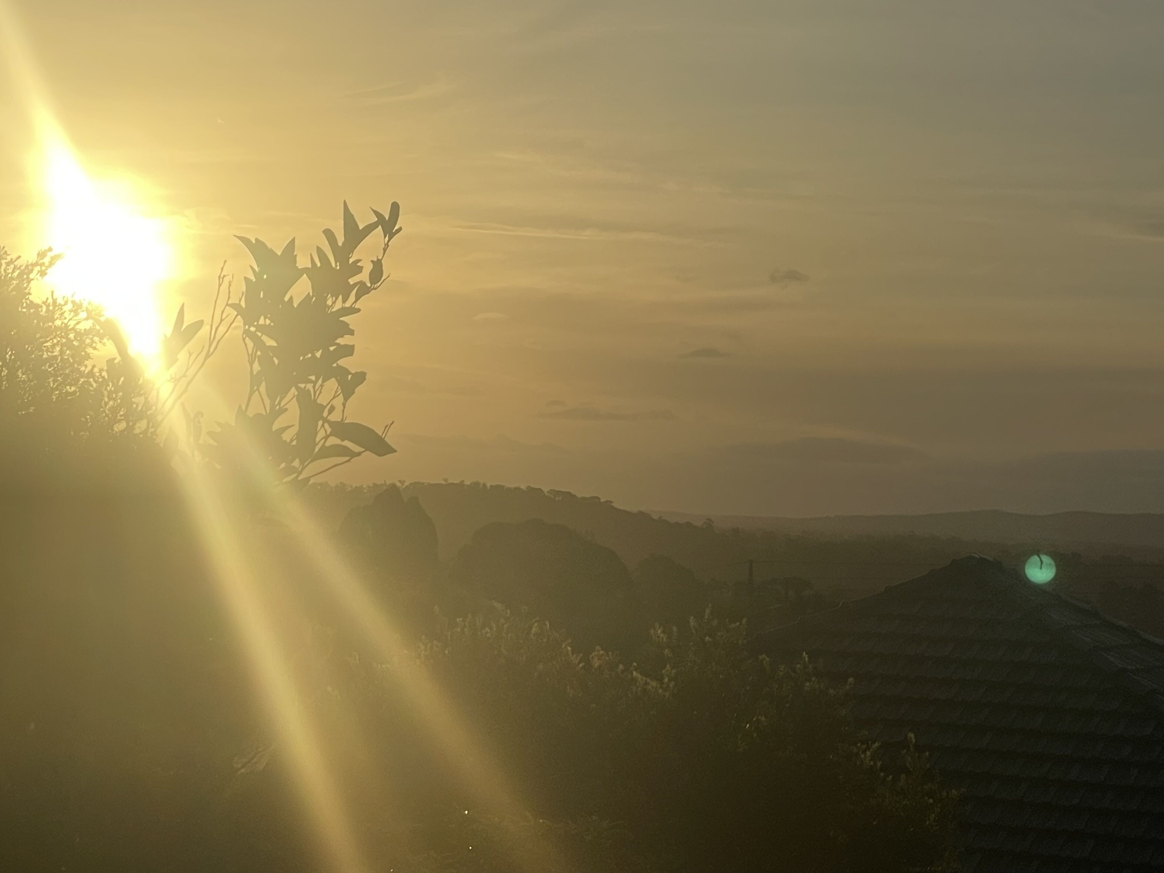 A landscape with a sunlit horizon and distant hills.