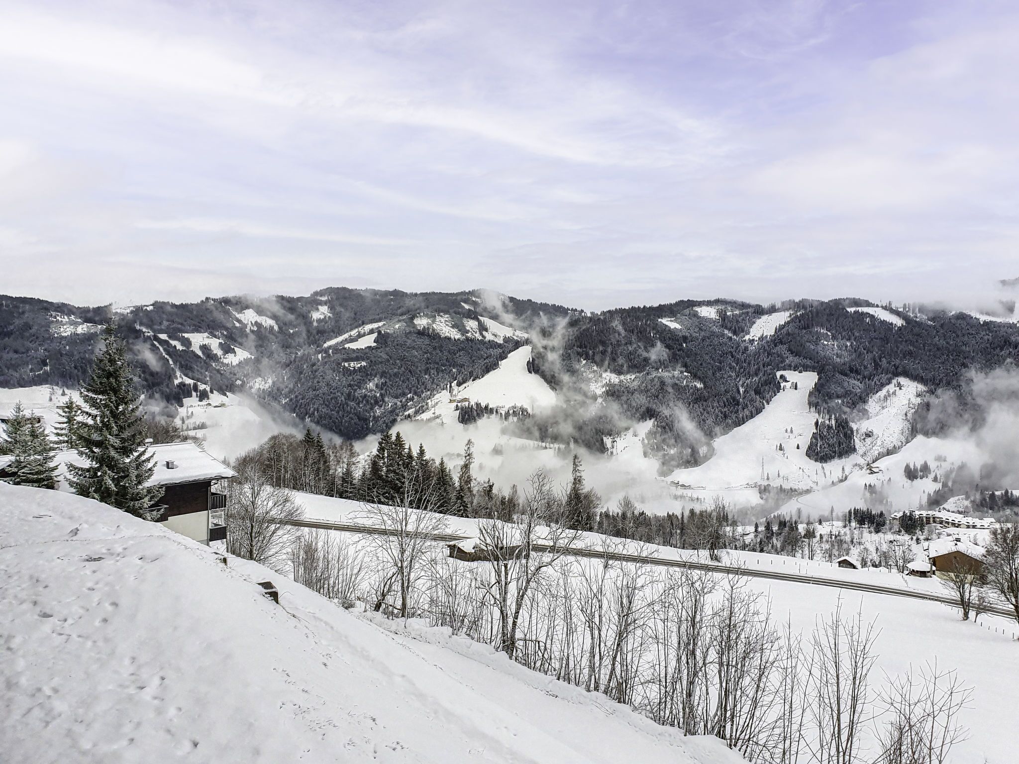 A snow-covered mountain landscape with a cabin and a ski slope.