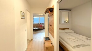 Habitación pequeña con cama, escritorio y un sofá al fondo.