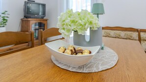 Une table à manger avec un bol de chocolats et un vase de fleurs blanches.