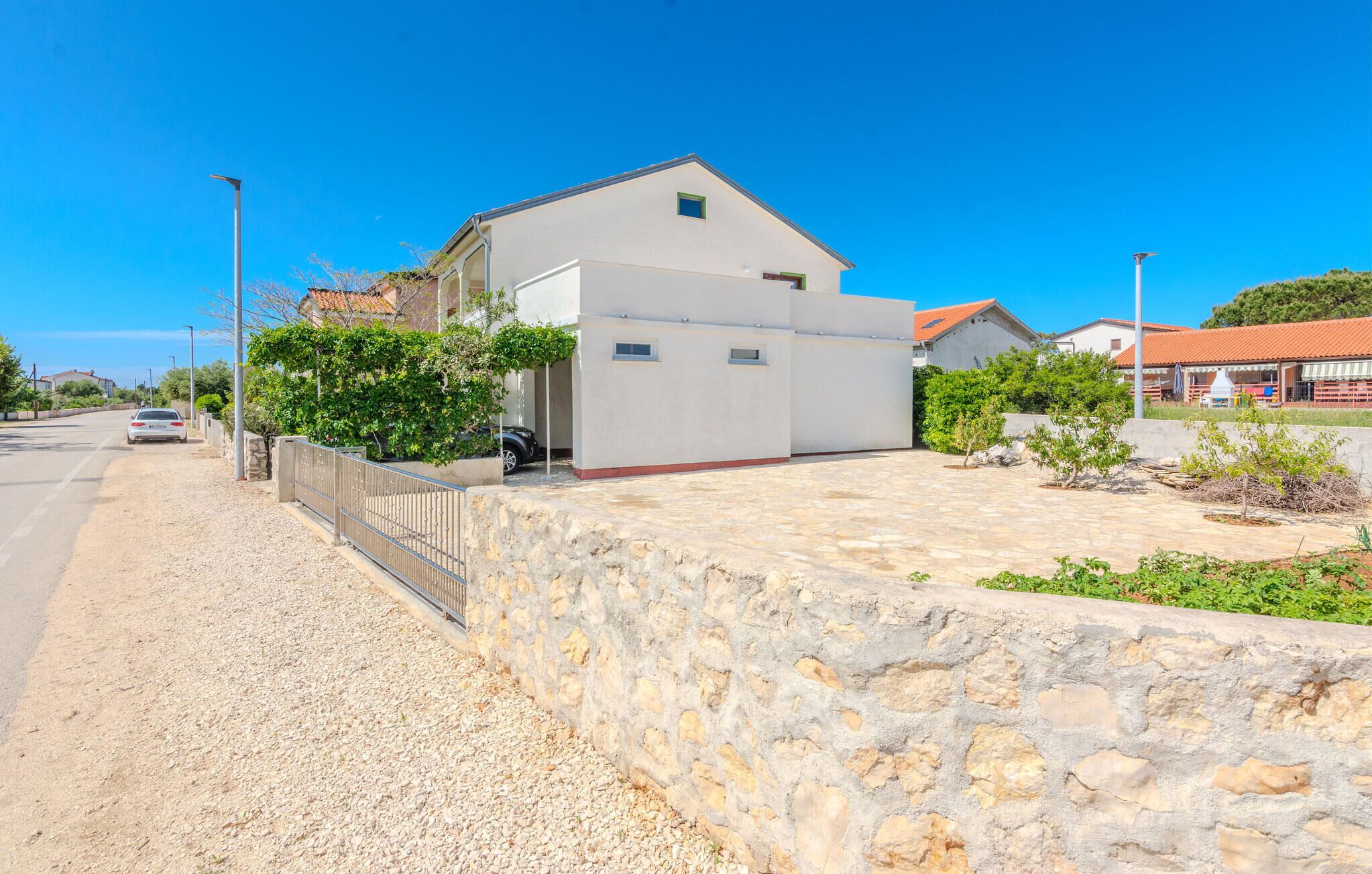 A building with a white exterior, a stone wall in front, and a clear blue sky.