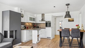 A modern kitchen with white cabinets, a built-in oven, and a dining area with a wooden table and two chairs. - Pet friendly apartment in Putbus with sauna (Putbus)