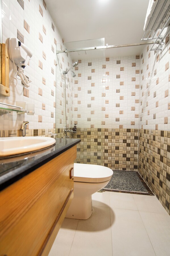 A bathroom with a sink, toilet, and shower area. -  Ocean Hotel (Da Nang)